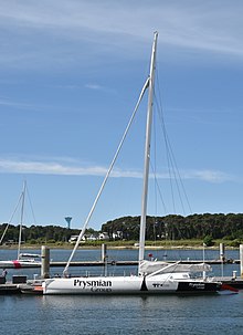 Vu en entier de profil, voilier tout blanc amarré au ponton.