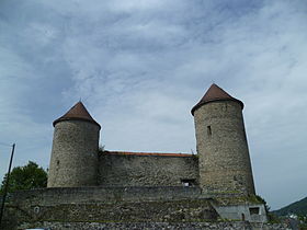 Photographie en couleurs de deux tours rondes reliées par une portion de courtine.