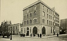 Photographie en noir et blanc de 1909 représentant l'immeuble où siège l'association. A gauche, une charrette tirée par un cheval.