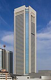 Mid-level view of a white, window-dotted, rectangular high-rise; the corners are cut and made of glass