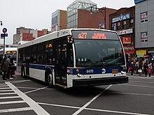 A Nova Bus LFS operating on the Q27 route in downtown Flushing on a cloudy day