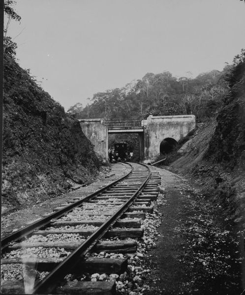 File:COLLECTIE TROPENMUSEUM Arbeiders poseren rondom een stoomlocomotief onder een brug over het spoor waarop zich een Europeaan bevindt TMnr 60047643.jpg