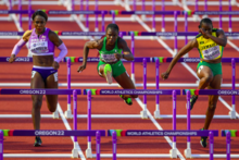 Frontal photo of Cindy Sember, Tobi Amusan, and Danielle Williams wearing national kits during a hurdling race