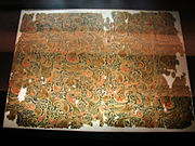 Frammento di stoffa con ricami di seta detti « di longevità (changshou) ». Han dell'Ovest La vedutaci mostra un frammento d'una trentina di centimetri di profondità. Insieme: 38 x 51 cm. Scoperto nel 1972, tomba 1, Mawangdui (Changsha, provincia dello Hunan). Museo provinciale dell'Hunan.