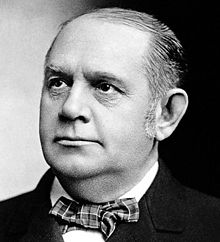 A black-and-white head-and-shoulders photograph of a respectfully turned-out middle-aged gentleman in a tartan-pattern bow-tie, white shirt and dark jacket