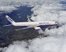 Side view of a twin-engine jet in flight, surrounded by white clouds