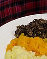 Le haggis et son accompagnement de légumes, devant le tartan du clan MacAlister.