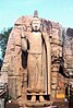 A statue of the Buddha, with a large rock face visible in the background