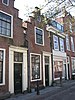 Pand met eenvoudige trapgevel met boven het venster van de zolderverdieping geblokte ontlastingsboog. Deuromlijsting met pilasters en hoofdgestel