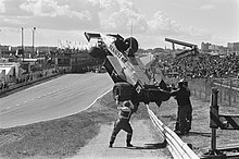 Photo en noir et blanc de l'évacuation d'une monoplace de Formule 1