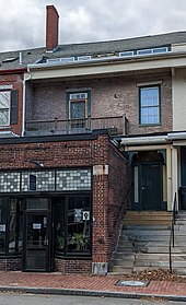 Two-and-a-half-story 19th-century brick row house with granite steps and a brick storefront attached