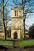 A tower with a round-arched doorway at the bottom, two-light bell openings at the top, surmounted by a low pyramidal roof