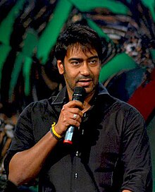 Ajay Devgn, speaking into a hand-held microphone