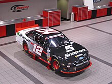 Black-and-white race car on jack stands in a shop