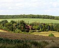 The house and gardens of Offley Chase surrounded by fields and rolling hills