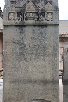 An inscribed stone with several people at the top