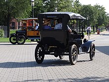 Two black Ford Model Ts on a brick road