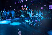 Photographie en couleurs, représentant des personnes en train de danser dans un établissement de nuit (le Brasil Tropical).