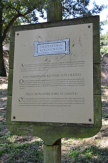 An information board provides background information on the Pauline Monastery ruins in three languages.