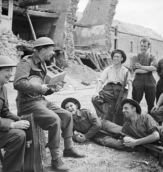 File:George Formby entertains troops in the ruins of a village in Normandy during an ENSA (Entertainments National Service Association) tour, 30 July 1944. B8256.jpg