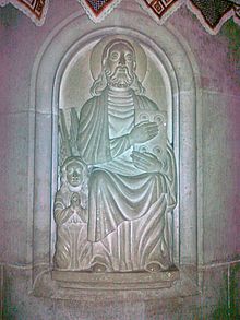 A relief depicting St Matthew holding a book and a small angel praying besides him