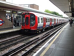 A grey, blue and red S8 stock train waiting at the platform at Harrow-on-the-Hill station