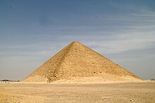 Photographie d'une pyramide à faces lisses s'élevant au milieu d'une plaine.