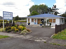 A white building with a blue roof and a photo of Key on the wall