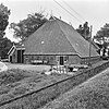 Kop-hals-rompboerderij tussen topgevels met onderkelderd kort voorhuis, zesruitsvensters en kleine lichtopeningen in de top onder zadeldak met topschoorstenen met borden