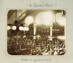 Looking down on assembled legislators on the floor of the hall with observers crowding an arcaded balcony.