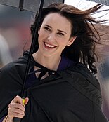 Rachel Brosnahan on set as Lois Lane holding an umbrella.