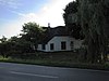 Deels gepleisterde hoeve met rechts een opkamer. Omlopend rieten schilddak. Langgerekte stal met pannen zadeldak en bewerkte daklijst