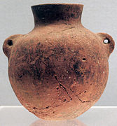 Terre cuite rouge à pâte fine, lissée. Culture de Peiligang, VIe millénaire av. J.-C.. Bouteille de type hu, à deux oreilles verticales perforées pour la corde. H. 11,2 cm. Musée de Shanghai.