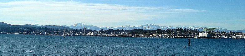 Puget Sound Naval Shipyard, as seen from across the water in Port Orchard. The mothballed ships are on the left, and the hammerhead crane is on the right.