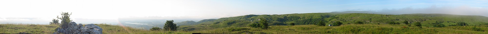 Panorama of grassy hills interspersed with limestone features and farm tracks.