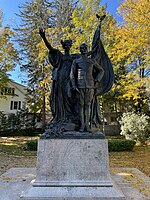 Bronze statue of a woman holding a flag behind a soldier