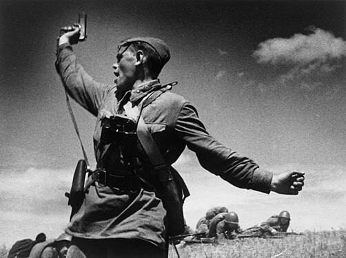 Black-and-white photograph of a Soviet military officer raising his pistol in the air