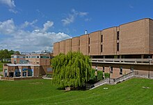 A photo depicting the outside of the library building for the University of Bradford, the sky is blue and the grass is green outside of the library in a closeby park.