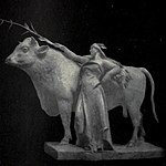 Statue of a woman holding a corn plant leaning on a cow