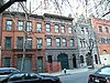 A row of four brick and stone townhouses with large lower doors