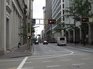 In downtown Cincinnati, traffic lights are mounted horizontally on gantries alongside illuminated traffic signs.