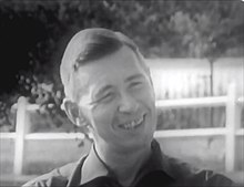 Image extraite d'un documentaire en noir et blanc montrant le visage de l'auteur souriant.