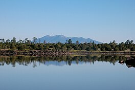 A lake, a coastline with trees, and mountains beyond