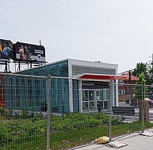 Photo of small, glass panelled subway station entrance with greenery beside it.