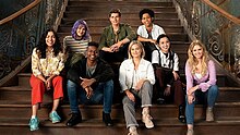 The cast members of the TV series Runaways and Cloak & Dagger sitting together on a staircase: From left to right: Ariela Barer as Gert Yorkes, Gregg Sulkin as Chase Stein, Rhenzy Feliz as Alex Wilder, Allegra Acosta as Molly Hernandez, Aubrey Joseph as Tyrone Johnson, Olivia Holt as Tandy Bowen, Lyrica Okano as Nico Minoru, and Virginia Gardner as Karolina Dean.