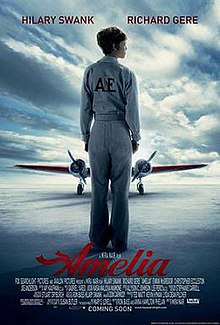 Hilary Swank as Amelia Earhart standing alone on the runway with her back turned wearing a flight suit and an aircraft filling the background