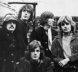 A black-and-white photo of five men standing in front of a brick wall.