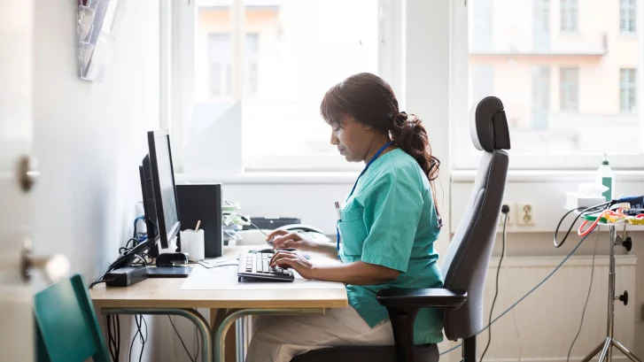 Nurse sitting at desk typing on keyboard