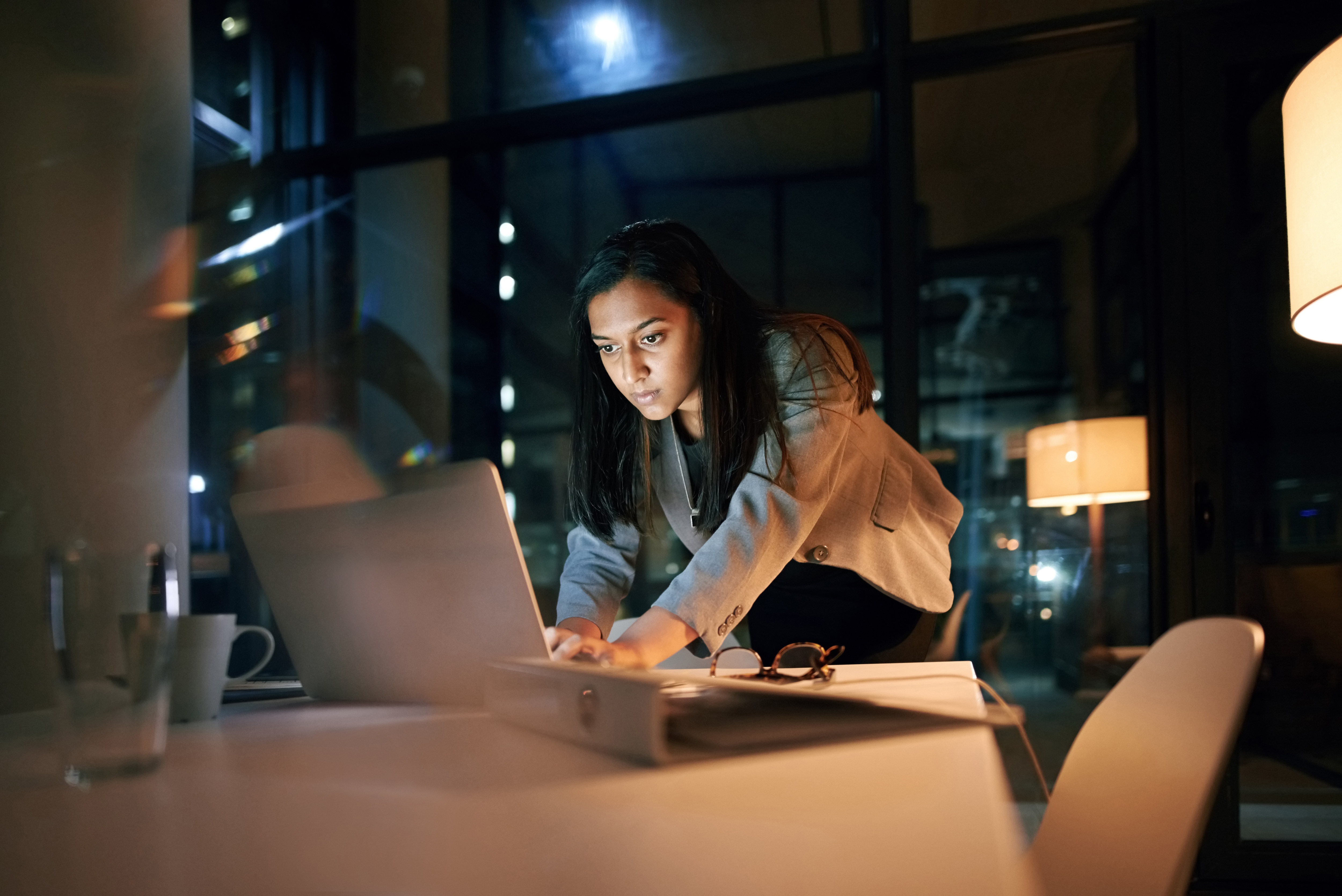 Pessoa digitando em um notebook em pé em uma mesa de conferência