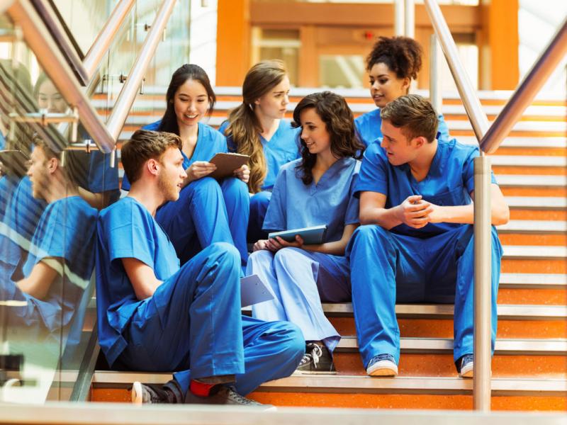 Group of medical school students in blue scrubs, sitting on the stairs